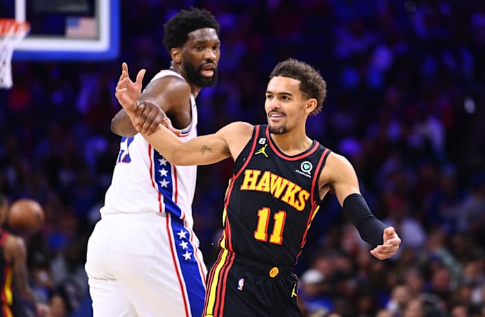 Hawks guard Trae Young reacts as 76ers center Joel Embiid grabs him.